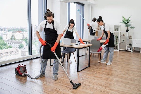 Cleaning crew vacuuming and dusting a bright modern office
