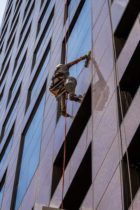 Window cleaner in a harness washing windows on a high-rise building