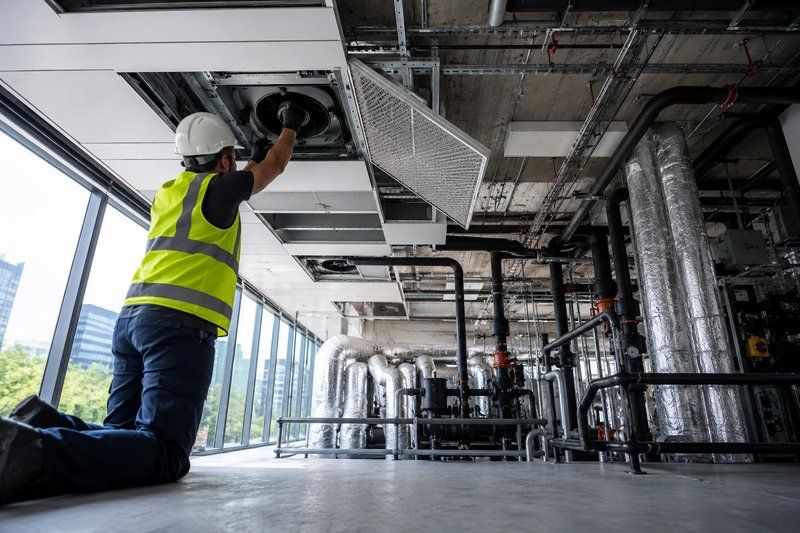 Maintenance technician servicing ceiling HVAC equipment